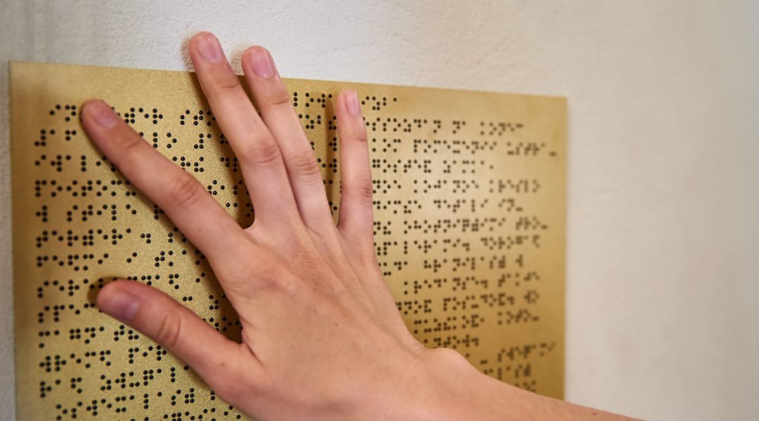 Woman reading braille text on a braille plate
